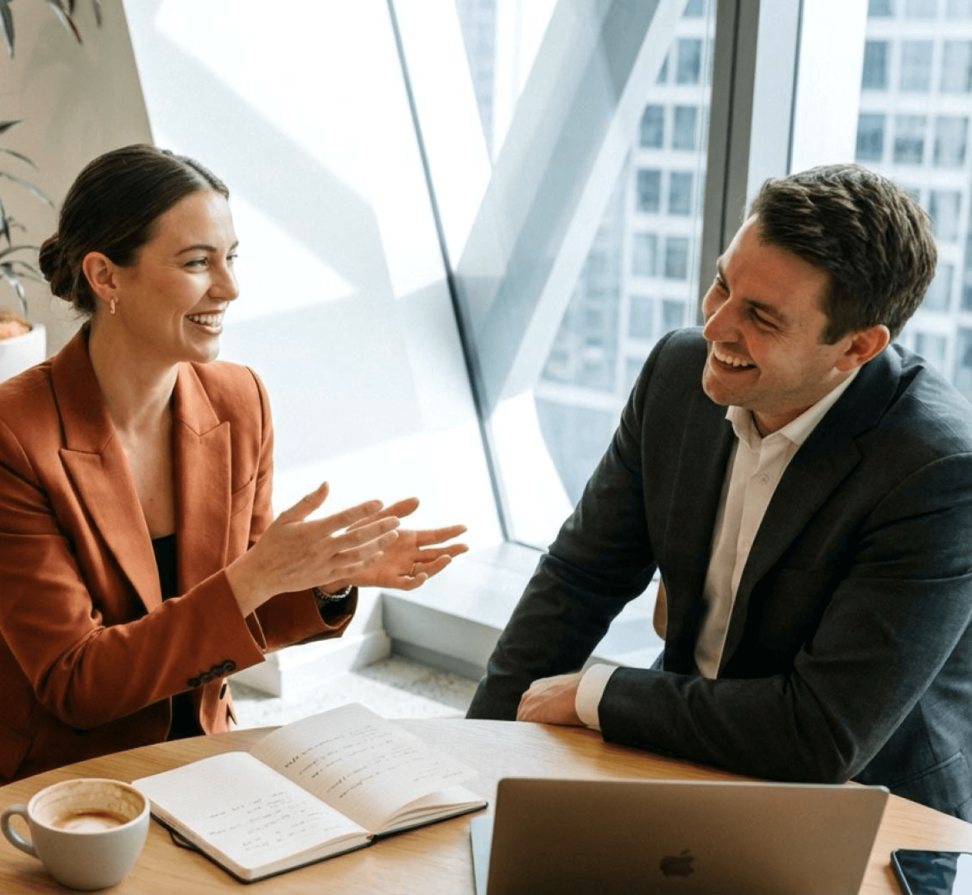 An advisor and a fund manager in conversation across a table with notes and coffee
